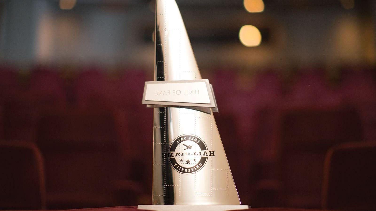 A gold, triangular statuette with the words Hall of Fame overlaid on the Full Sail University logo.