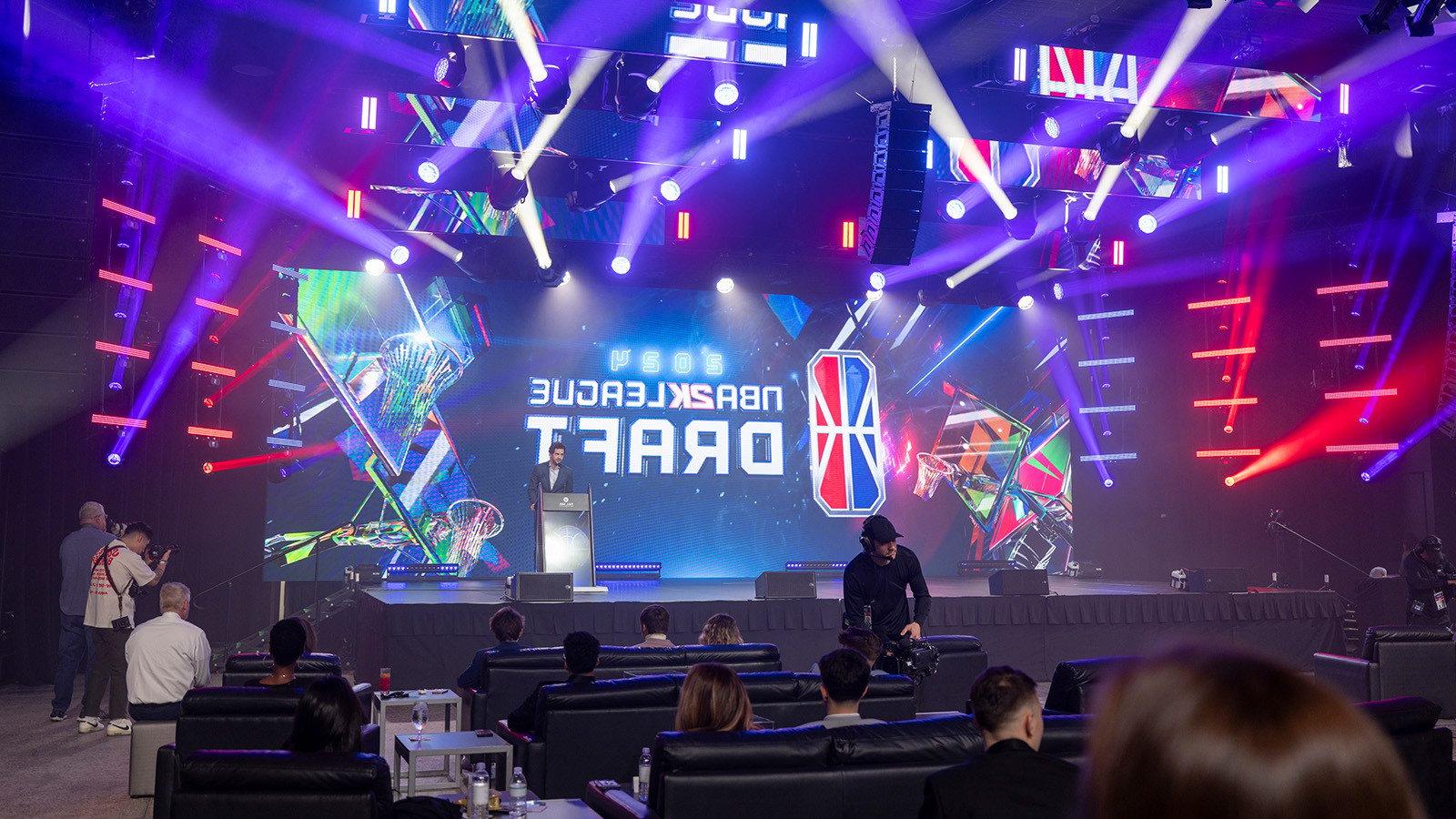 NBA 2K联盟首席执行官安德鲁·珀尔马特站在舞台前的大屏幕上，屏幕上有NBA 2K联盟选秀大会的标志.