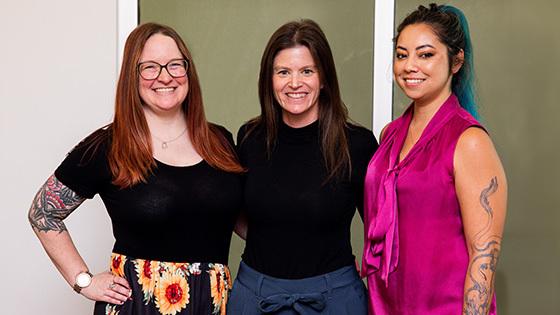 三位来自《Full Sail》的女性获得了今年的游戏奖提名，她们站在一起，对着镜头微笑.